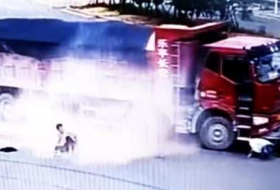 Китаец на мотороллере попал под два грузовика и чудом уцелел - ВИДЕО
